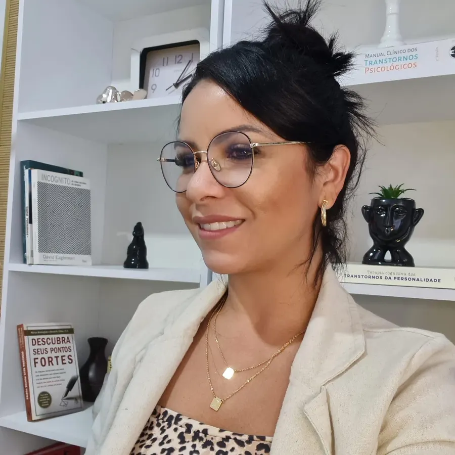 Aline Silva, psicóloga, sorrindo, com estante de livros ao fundo